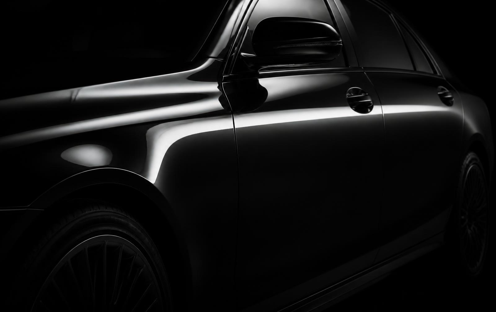The same black sedan door with mirror-flat corrected paint after three-stage correction